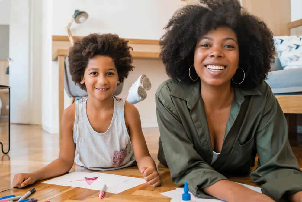 smiling woman and son laying on floor doing creative project