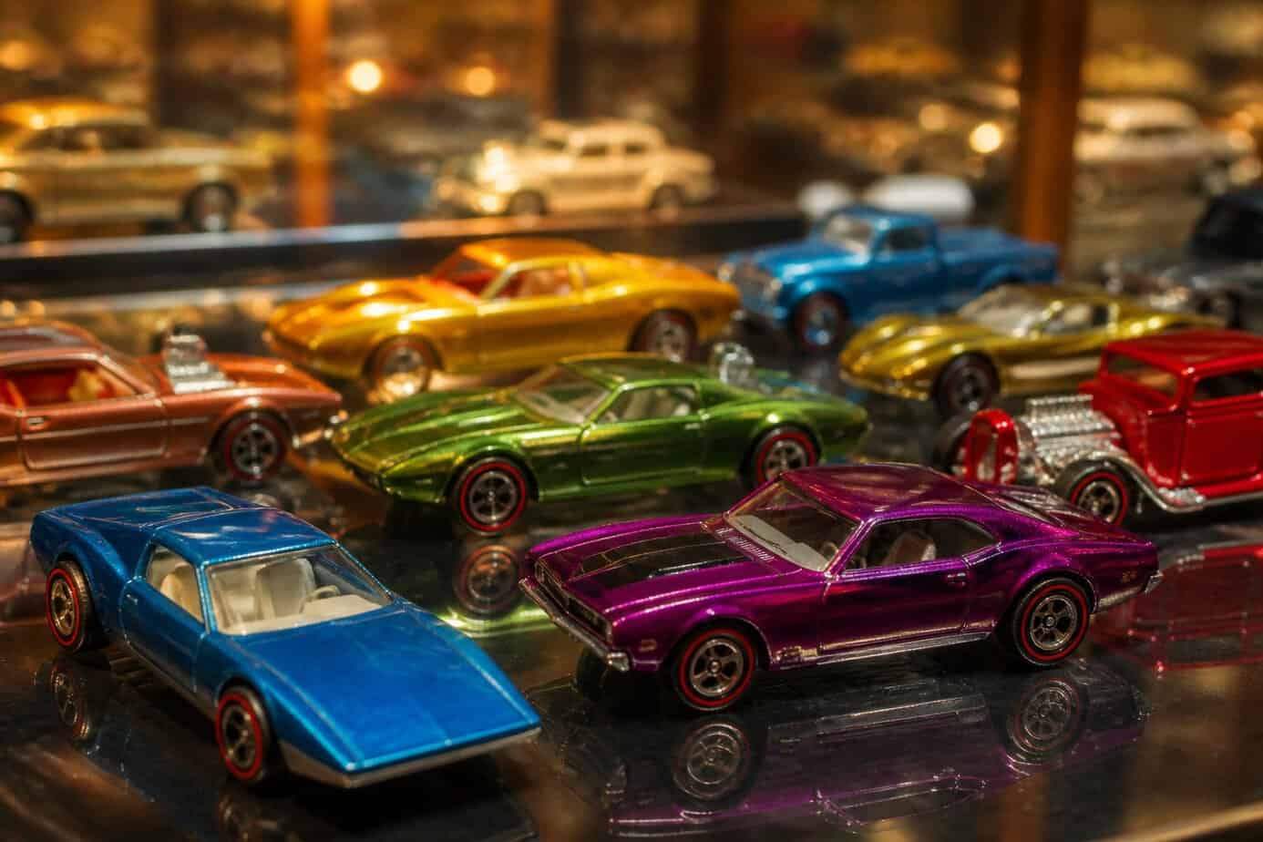 A collection of colorful Hot Wheels Redline toy cars from the 1980s arranged on a reflective surface.