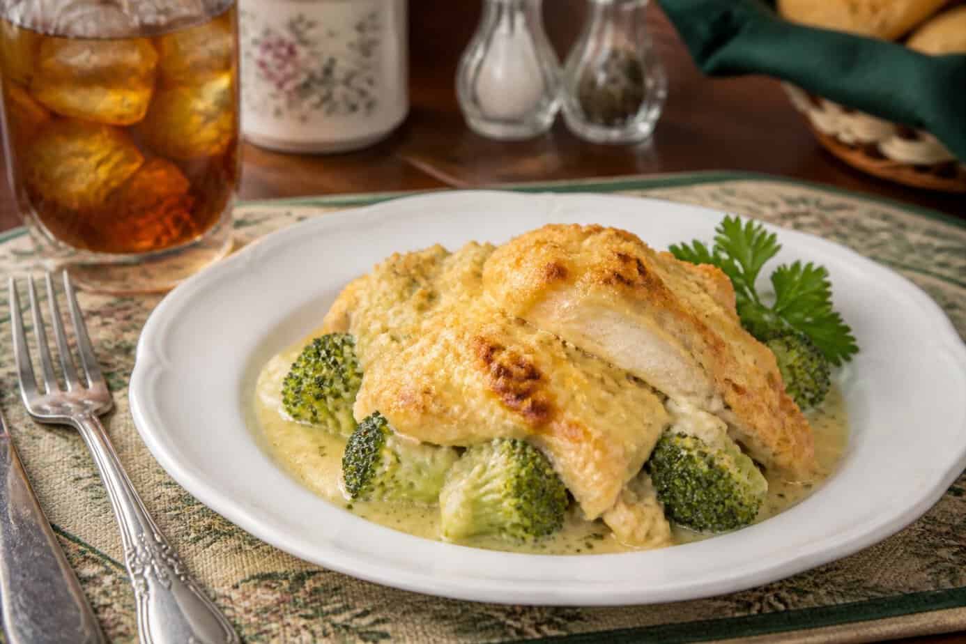 A plate of chicken divan with broccoli and melted cheese on a family dining table.