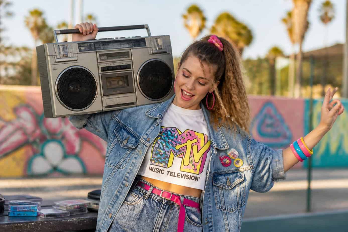 A young person dancing outdoors with a large vintage boombox with oversized speakers.