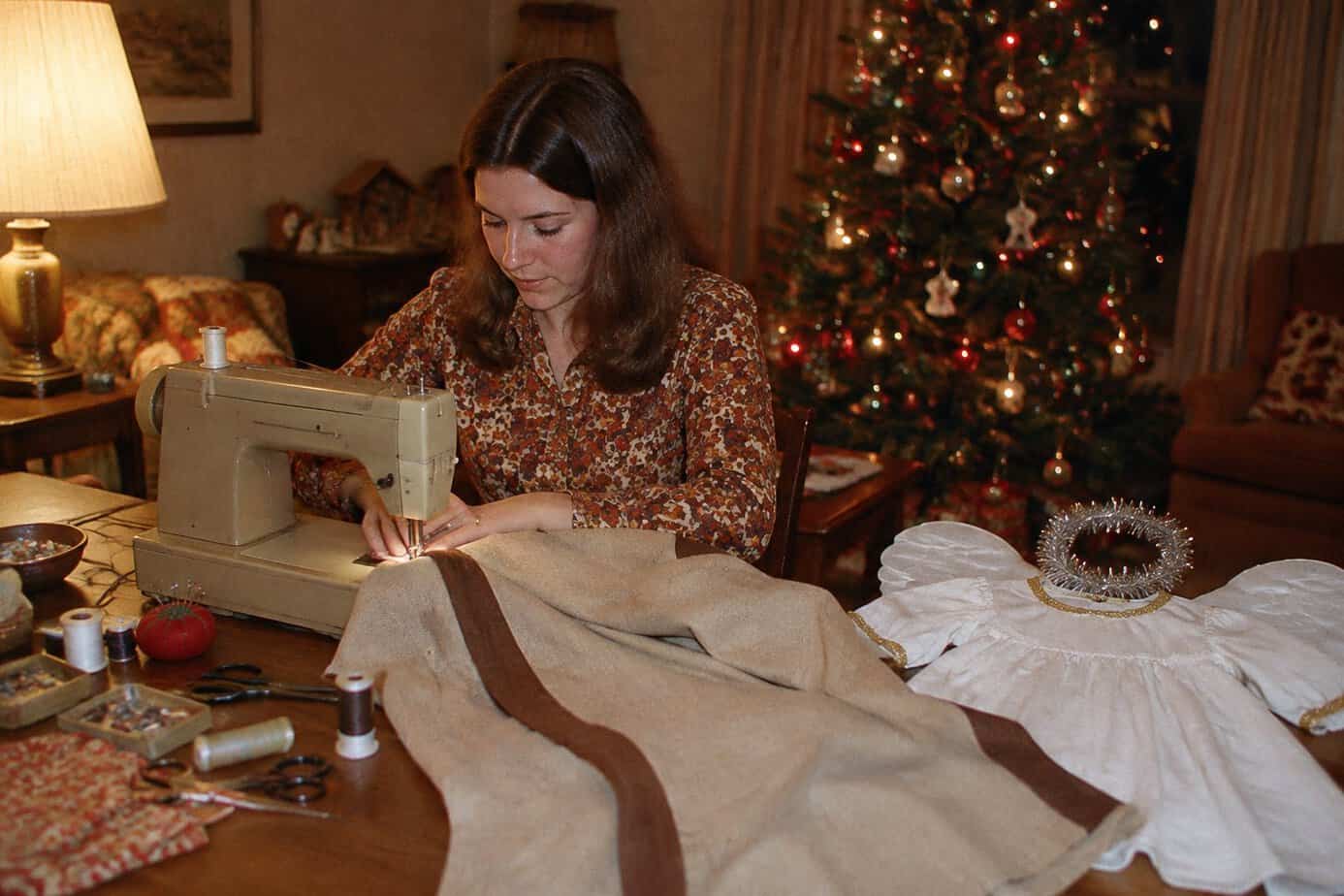 A young mother sews a shepherd robe and an angel costume for a church Christmas pageant in a 1970s living room.