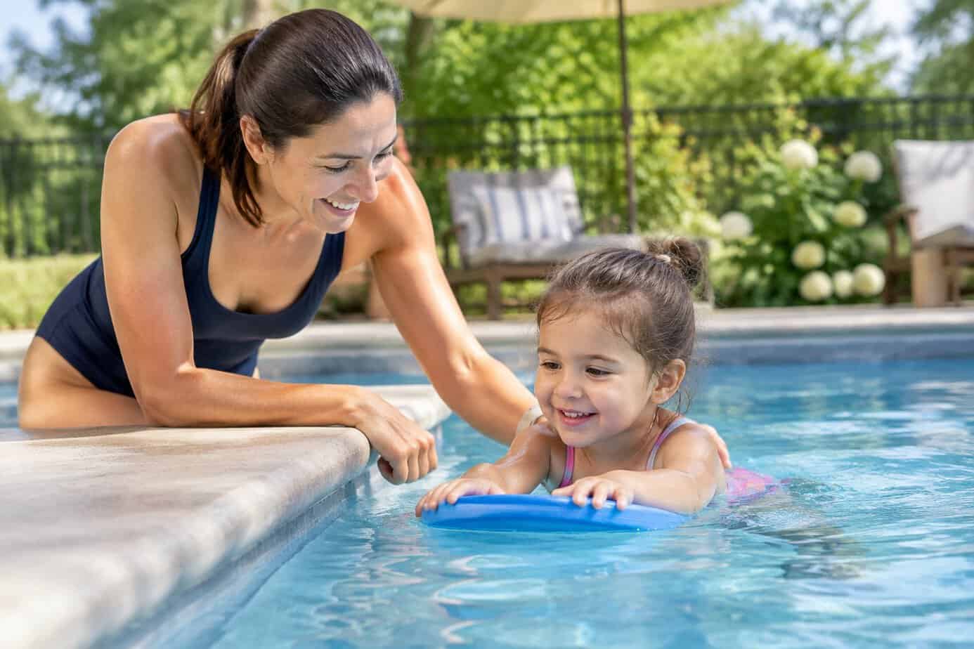 A parent watches a young child playing in a shallow pool and shows them how to stay safe.
