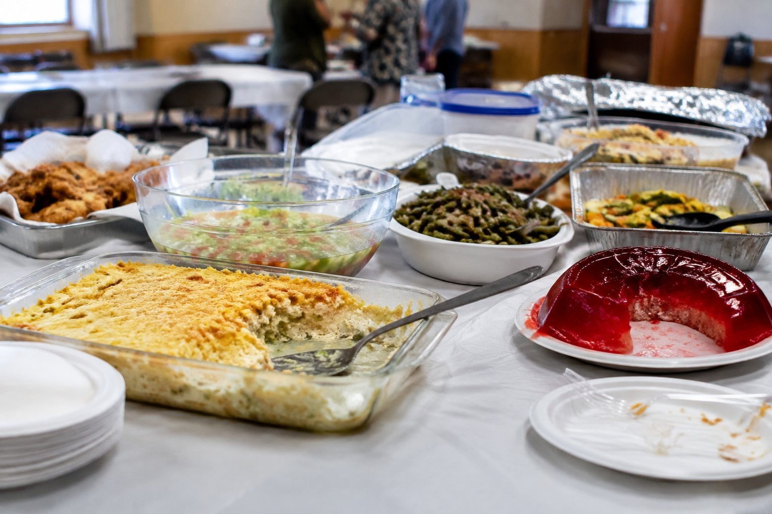 A buffet table holds several unappealing leftover dishes and untouched food containers.