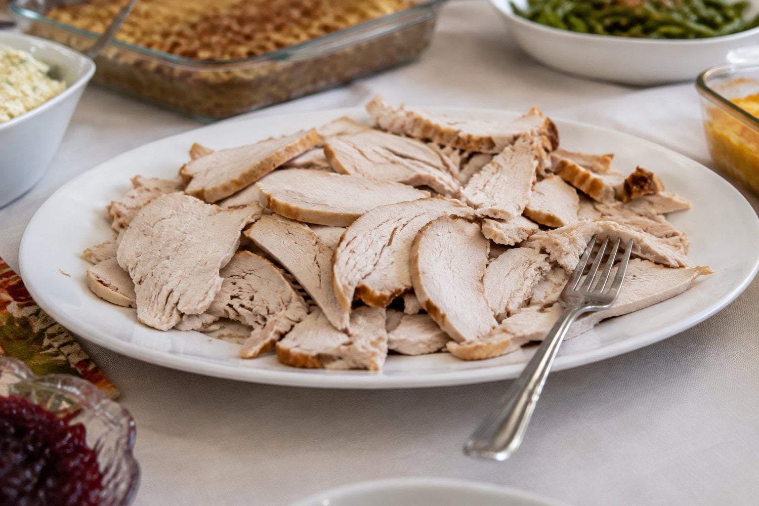 Dry slices of turkey sit on a serving platter at a buffet.