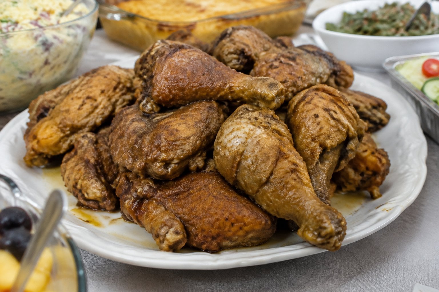 A platter of limp, greasy fried chicken on a potluck buffet table.